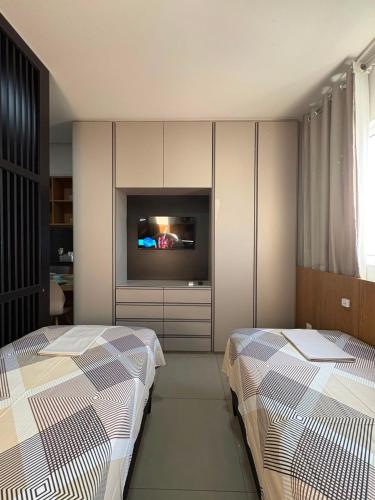two beds in a room with a tv and a bedroom at Westfit Barreto 01 in Mossoró