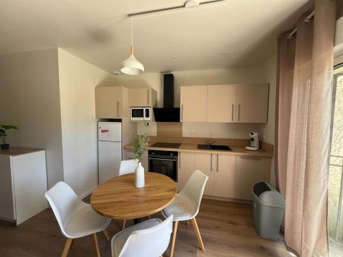 a small kitchen with a wooden table and white chairs at Logement en campagne in Bédarrides