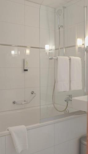 a bathroom with a shower and a bath tub with towels at Hotel Weisses Kreuz in Interlaken
