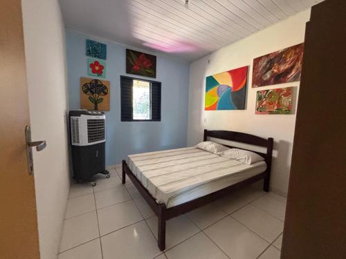 a bedroom with a bed and paintings on the walls at Casa da Santa Marta in Goiás