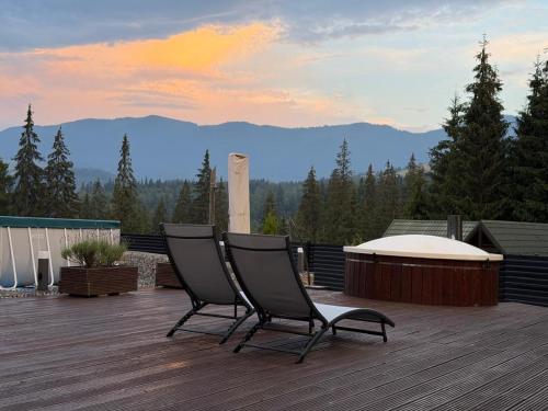 two chairs sitting on a deck with a view of mountains at UnderДіл in Krivopolʼye