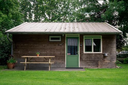 a small shed with a picnic table and a green door at Chalet - Camping 't Dekske in Wintelre