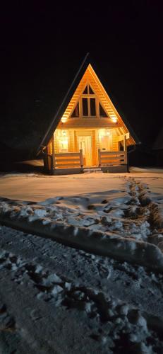 a cabin in the snow at night with lights at BB CHALET in Kolašin