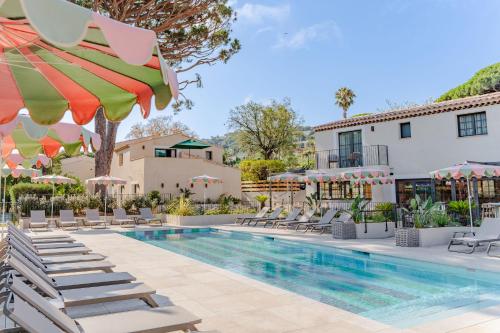 a resort pool with lounge chairs and umbrellas at Capucines Hotel Saint Tropez in Saint-Tropez