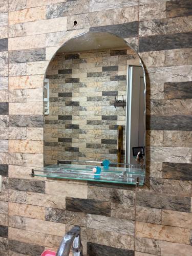 a bathroom with a mirror on a stone wall at Nikola apartment ambrolauri in Ambrolauri