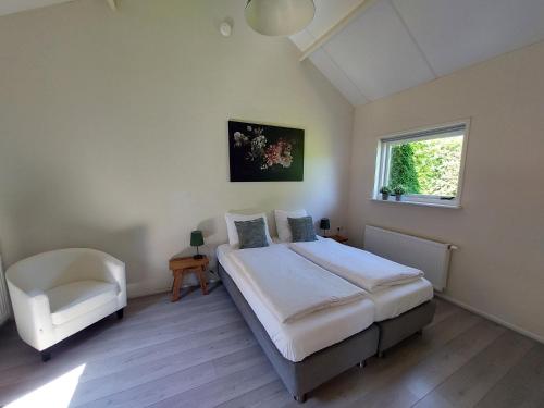 a bedroom with a bed and a chair and a window at Huisje nr. 18 met jacuzzi in Putten