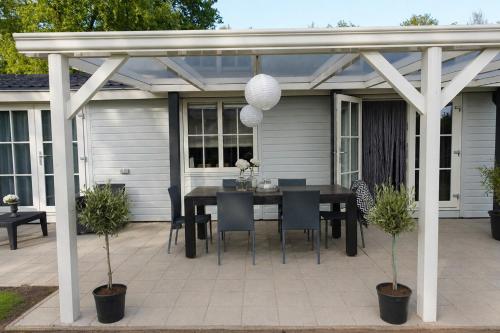 a patio with a table and chairs under a pergola at Vechtdalchalet de Berk, 5 sterrenpark Capfun Stoetenslagh in Rheezerveen