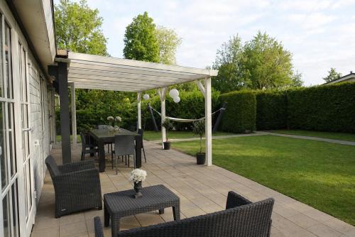 a pergola with a table and chairs on a patio at Vechtdalchalet de Berk, 5 sterrenpark Capfun Stoetenslagh in Rheezerveen