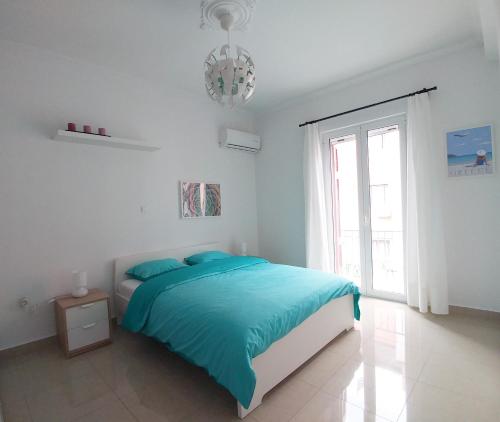 a white bedroom with a blue bed and a window at KYMA Apartments - Athens Acropolis 1 in Athens