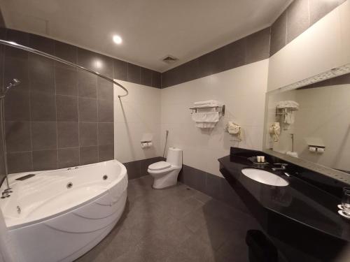 a bathroom with a tub and a toilet and a sink at Khách sạn APPLAZA in Hòa Bình