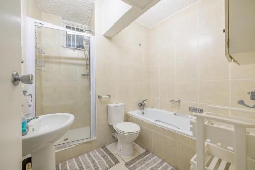 a bathroom with a toilet and a tub and a sink at Breakers Resort 130 Umhlanga Beachfront in Durban