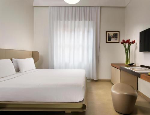 a hotel room with a white bed and a desk at Palazzo Montemartini Rome, A Radisson Collection Hotel in Rome