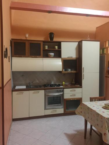 ナポリにあるDon Vincenzo's homeの白いキャビネットとテーブル(テーブル付)が備わるキッチン