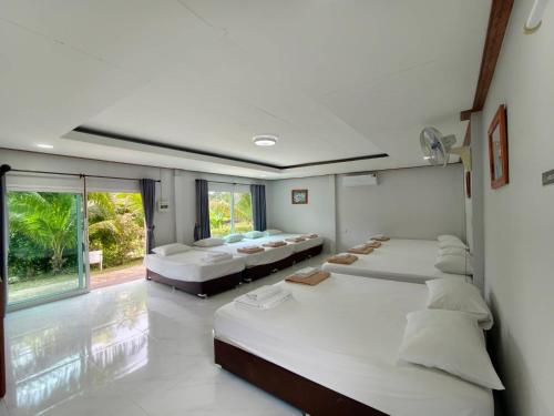 a bedroom with three beds and a large window at Lamphurai Riverside Resort and Spa in Trat