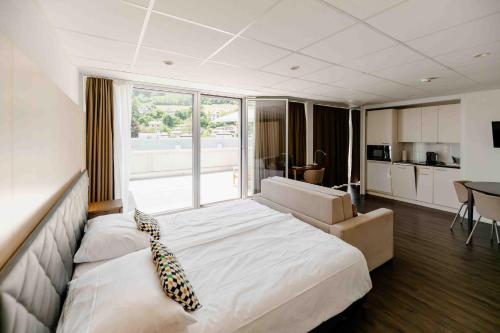 a large bedroom with a large bed and a kitchen at Los Lorentes Hotel Bern Airport in Belp