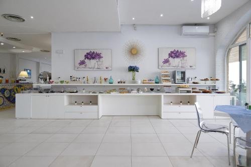 a kitchen with white cabinets and a table and chairs at Hotel Centro Congressi Polo Nautico in Salerno