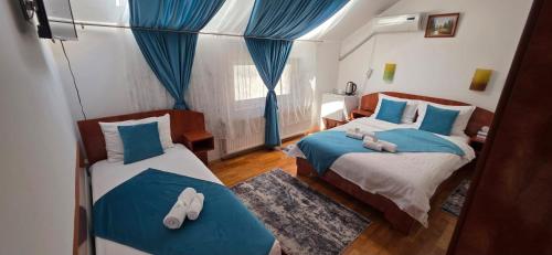 a bedroom with two beds with blue and white pillows at Motel Buti in Sighetu Marmaţiei
