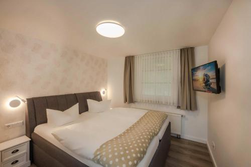 a bedroom with a large white bed and a window at Waldsiedlung Waldhaus App 2.2 in Korswandt