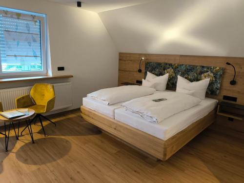 a bedroom with a large bed and a yellow chair at Landgasthaus Jägerhof in Absberg