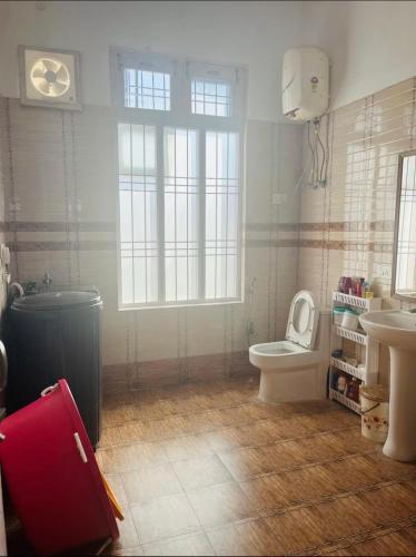 a bathroom with a toilet and a sink and a red suitcase at White View Park in Dharmsāla