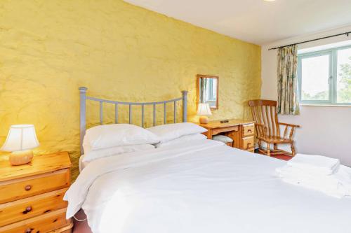 a bedroom with a large white bed and a desk at Wren Cottage in Cowbridge