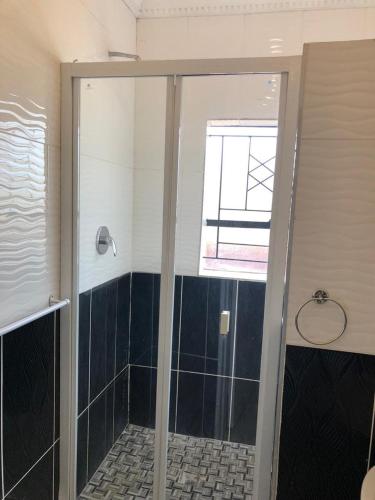 a shower with a glass door in a bathroom at Leeba Apartments in Maseru