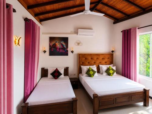two beds in a room with pink curtains at Sea Bloom Villa in Kamburugamuwa