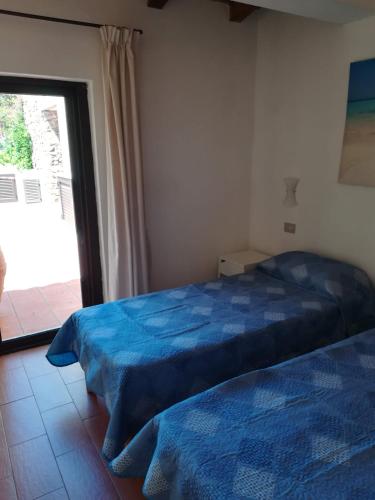 a bedroom with two beds and a sliding glass door at Visit San Teodoro in San Teodoro