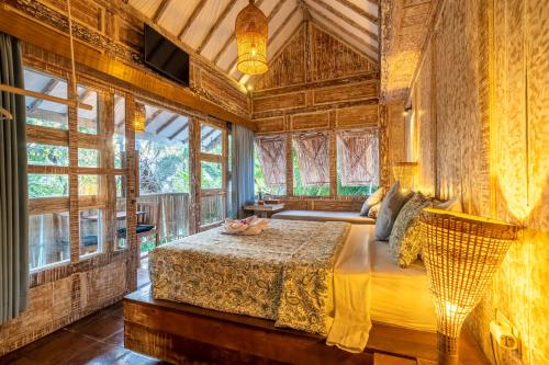a bedroom with a bed in a room with windows at Ortigia Tropical Lodge in Gili Trawangan