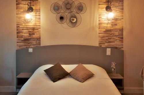 a bedroom with a large bed with two pillows at Logis Hôtel - Auberge du Pastel - Hôtel 3 étoiles et Restaurant in Nailloux