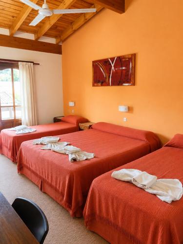 two beds in a room with orange walls at Hotel Gran Lucerna in Valle Hermoso