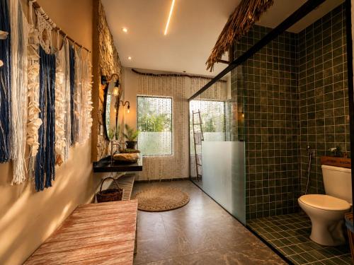 a bathroom with a shower and a toilet and green tiles at Pura Vida Hotel in Itarema