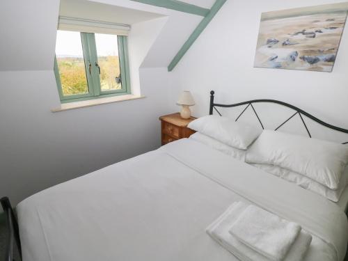 a bedroom with a white bed and a window at Swallow Cottage in Cowbridge