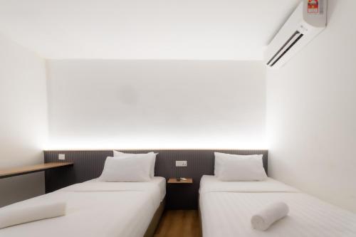 two beds in a room with white walls at T Hotel SP Pekan Lama in Sungai Petani