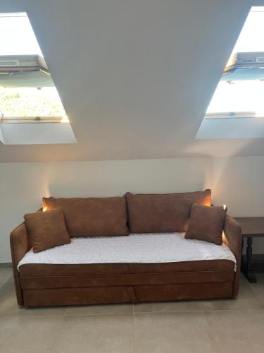 a brown couch in a room with two windows at Robinson Medvidina Bay in Zastražišće