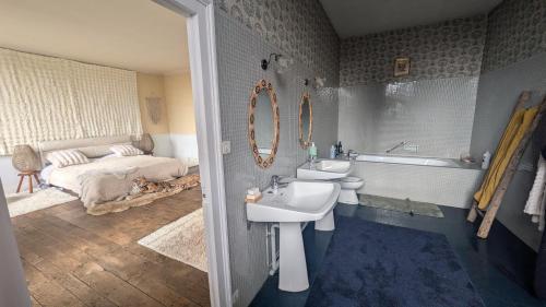 a bathroom with a sink and a tub and a bed at L'héritage in Champdeniers