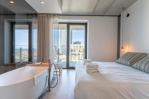 a bedroom with a bathtub and a bed with a view at Suite O in Ostend
