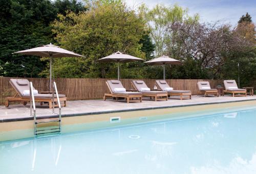 a group of chairs and umbrellas next to a pool at The Bath Priory - A Relais & Chateaux Hotel in Bath