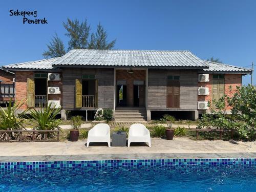 a house with two chairs and a swimming pool at Sekepeng Penarek in Kampung Penarik