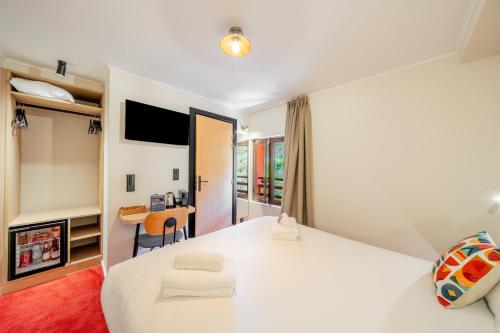 a hotel room with a large white bed and a desk at Logis Hotel de l'Artuby in Séranon