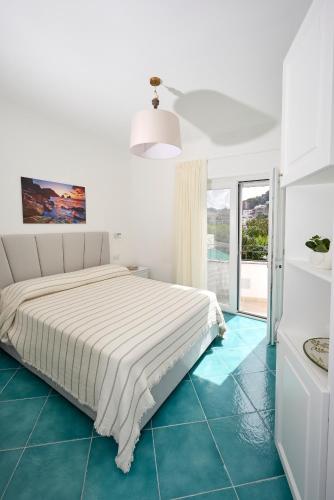 a white bedroom with a bed and blue tile floors at La Marilena Penthouse in Capri
