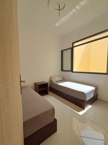 a bedroom with two beds and a large window at Résidence Maya 1 près de la plage in Ras El Ma