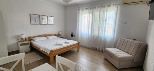 a bedroom with a bed and a couch and a chair at Apartmani Vidakovic in Igalo
