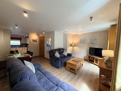 a living room with a blue couch and a tv at The Galleries No 3 in Spean Bridge