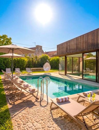 a swimming pool with chairs and an umbrella at Villã - Casas de Campo in Paredes