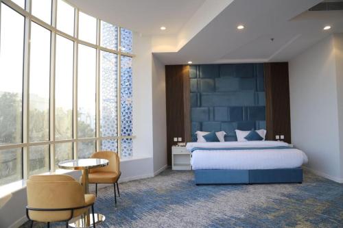 a bedroom with a bed and a large window at Areen Almatar Serviced Apartments شقق ارين المطار للشقق المخدومة in Jeddah