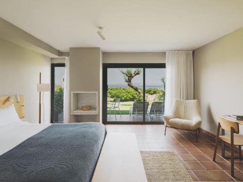 a bedroom with a bed and a desk and chairs at Hotel Es Blau Des Nord in Colonia de Sant Pere