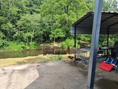 a patio with a table and chairs next to a river at Camper with Queen and bunk bed in Robbinsville