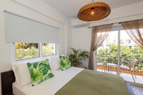 a bedroom with a white bed and large windows at Olive Grove Apartments in Larnaca