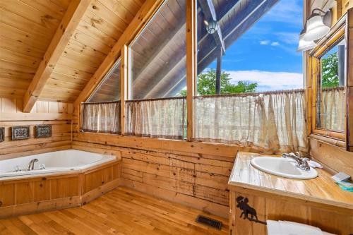 a bathroom with a tub and two sinks and a window at Above It All #38 by Venture Smoky Mountains in Sevierville